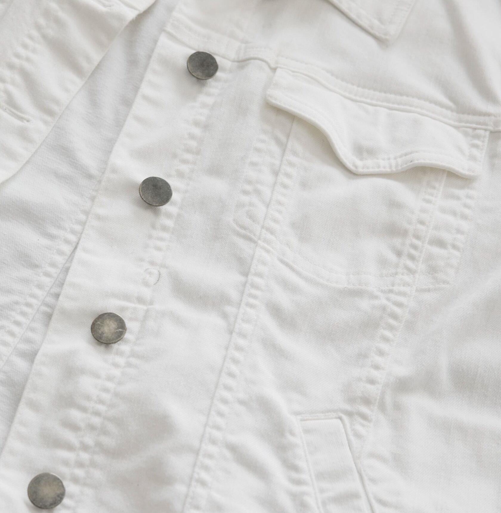 A white denim jacket with a flaw circled in pen. A white denim jacket with a flaw circled in pen.