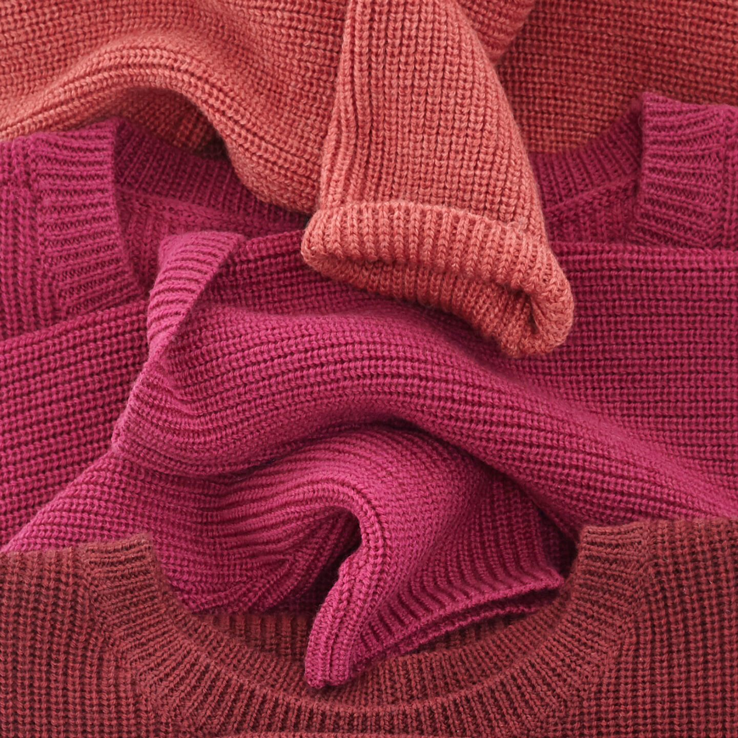 Berry colored sweaters folded in a row. Berry colored sweaters folded in a row.
