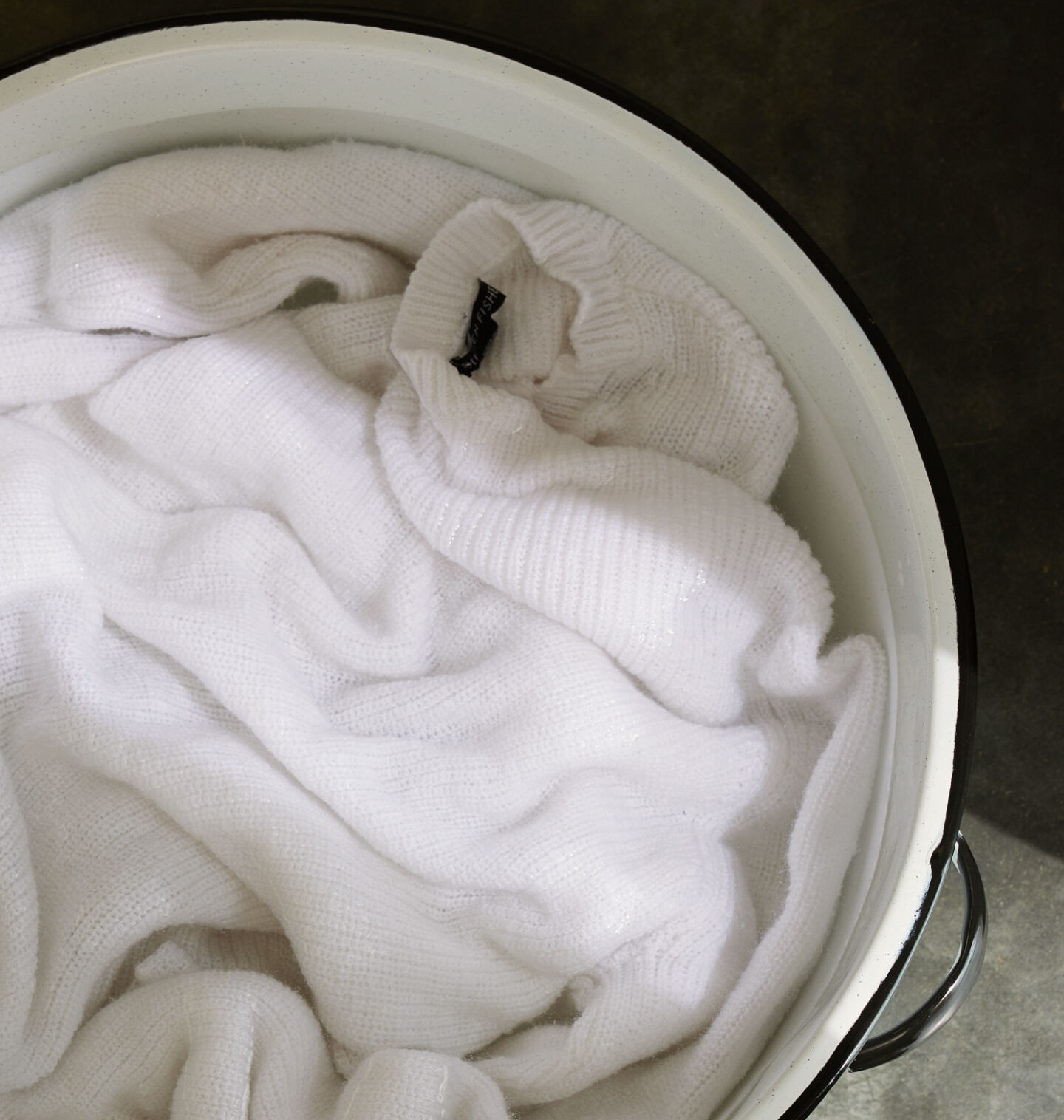 Beige sweater in basin of soapy water. Beige sweater in basin of soapy water.