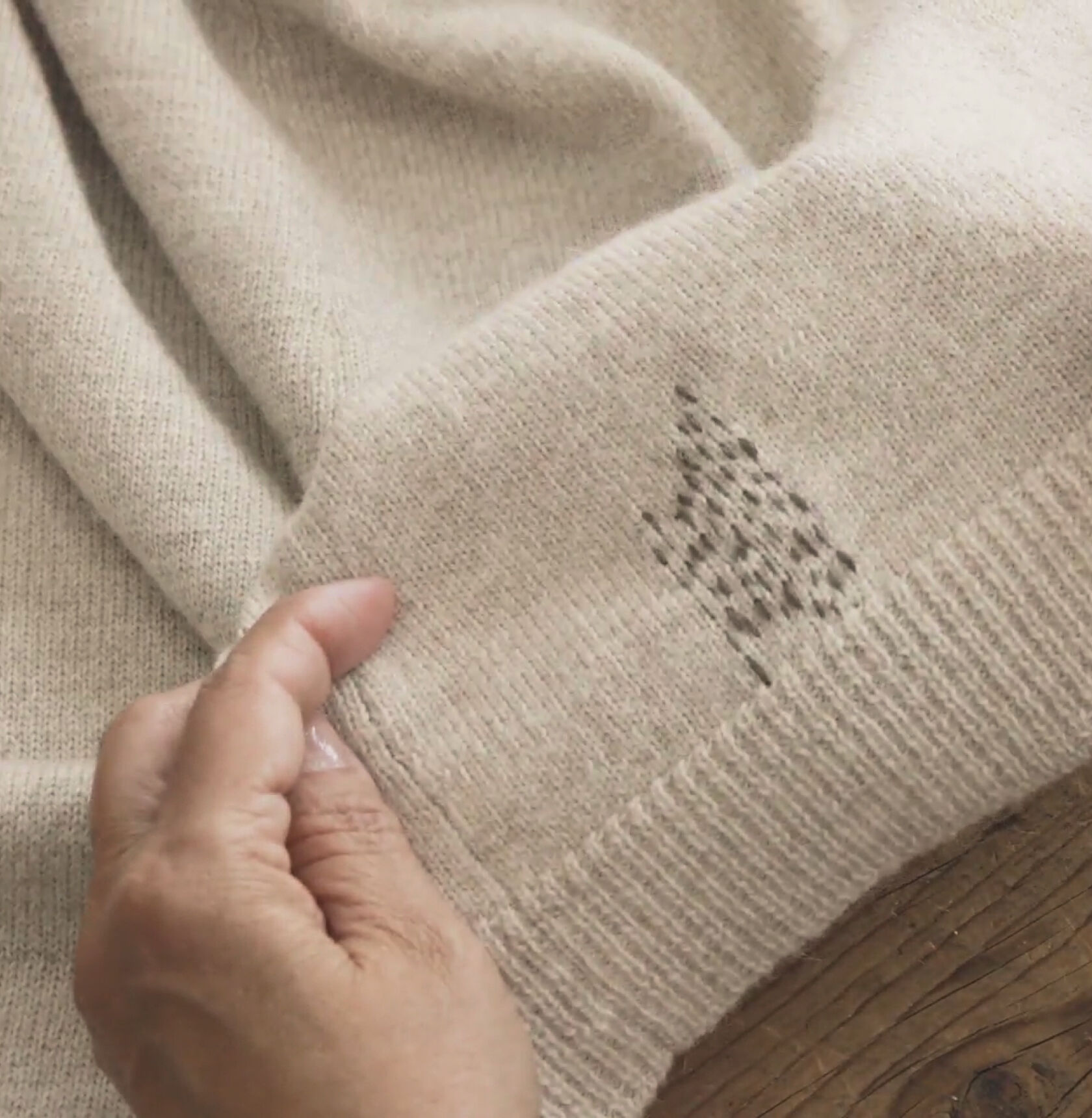 Completed visibly mended running stitch pattern on a beige sweater. Completed visibly mended running stitch pattern on a beige sweater.
