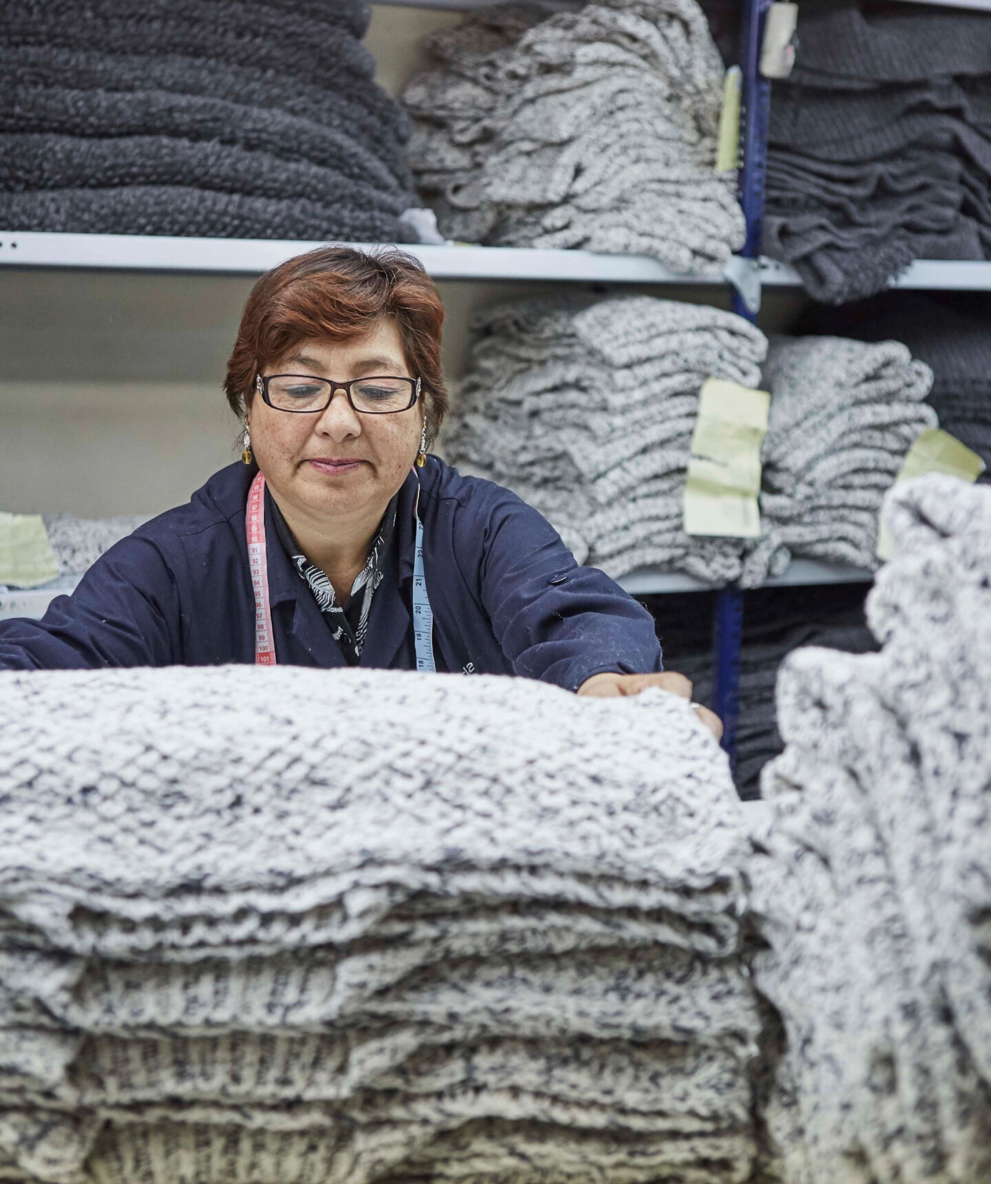 Woman folding sweaters at a knit factory. Woman folding sweaters at a knit factory.