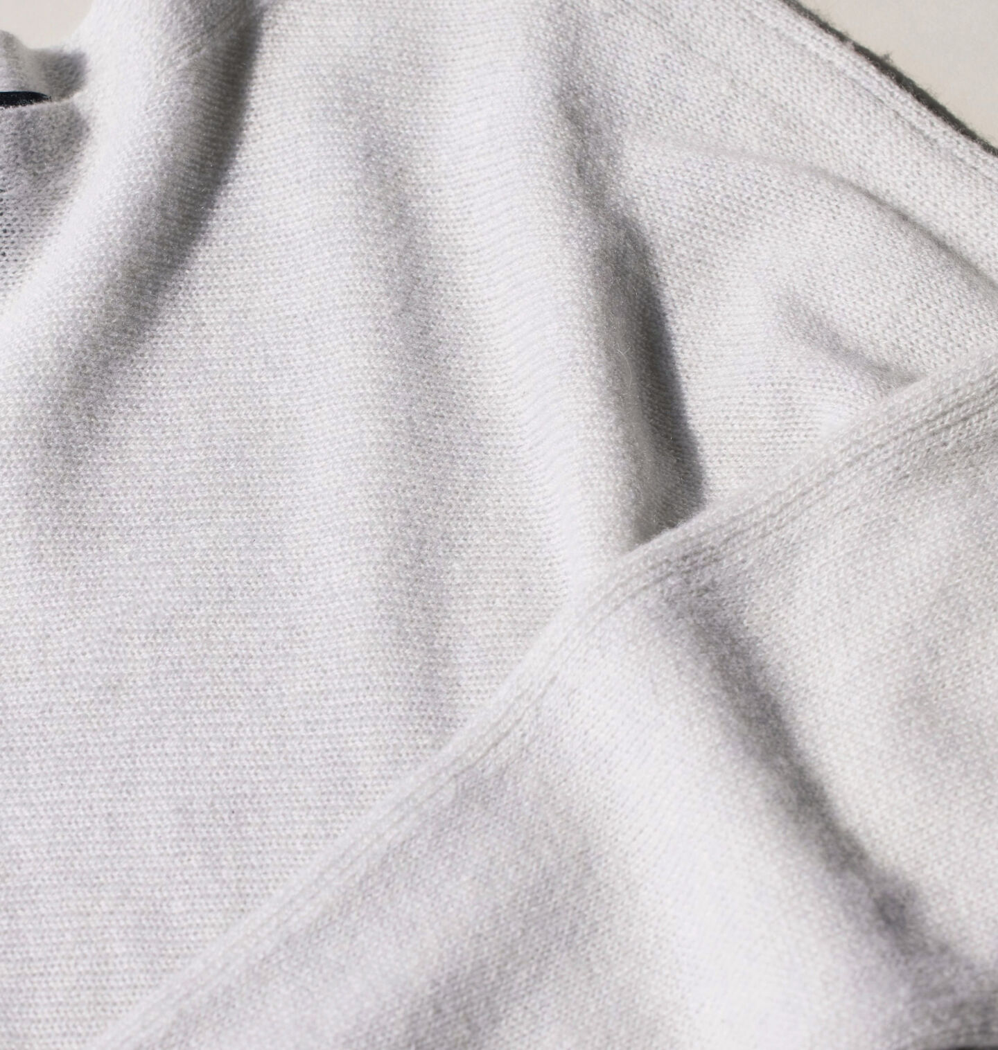 A woman's white knit sweater laid flat. A woman's white knit sweater laid flat.